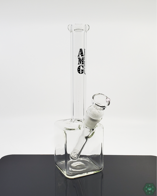 AMG Glass 9” Cube Base Beaker | Compact, 7-Hole Perc Filtration | 14mm Joint. This 9" Cube Base Beaker by AMG Glass includes a 7-hole perc for smooth hits, a 14mm female joint, and a removable downstem for easy maintenance. Available in multiple color accents.