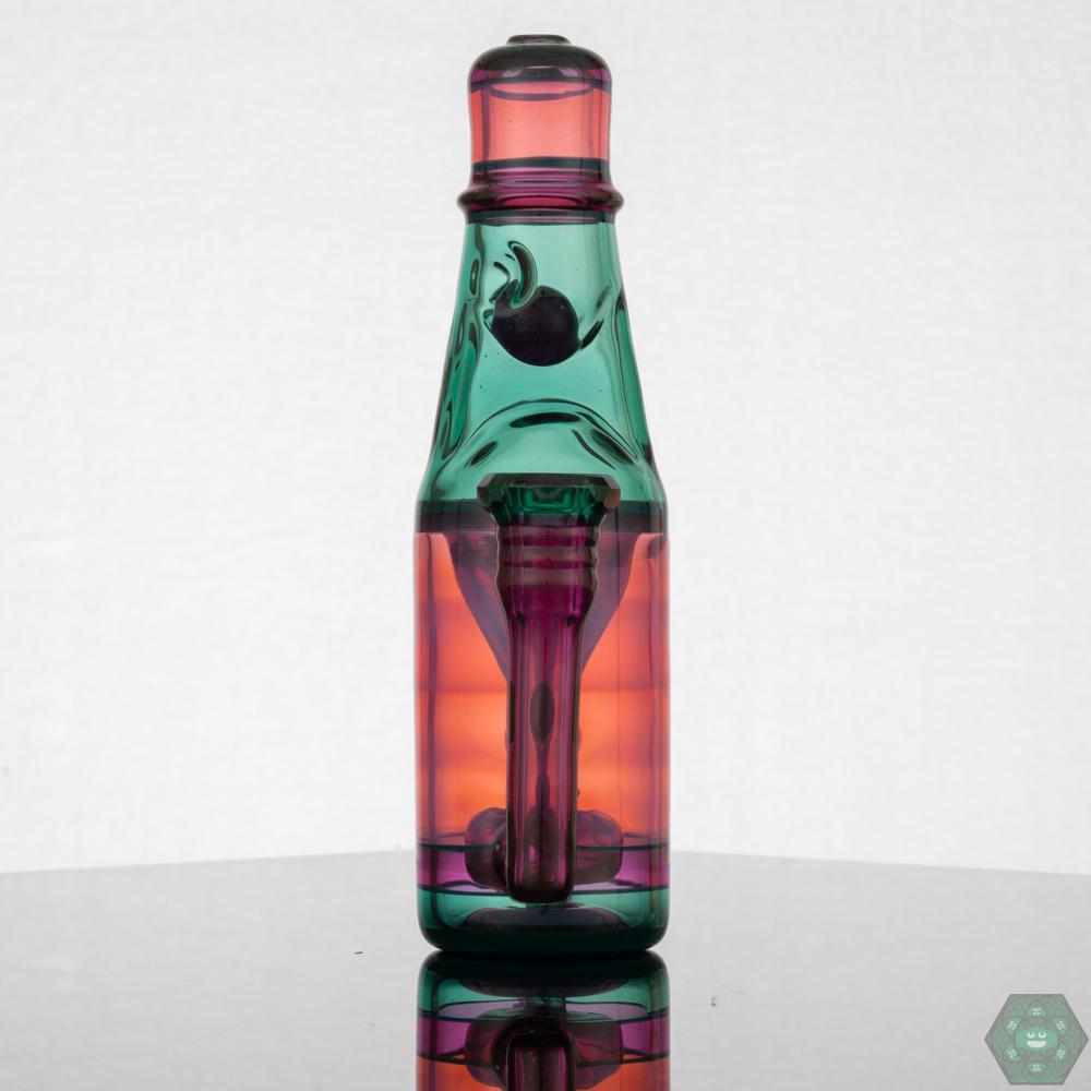 Jack Blew – Mini Ramune Bottle Recycler with 4-Hole Perc. Precision Design: Crafted by Jack Blew Glass, showcasing expert glasswork. Efficient Filtration: Equipped with a 4-hole perc, 10mm female 90° joint, and single drain for smooth recycling. Compact & Stylish: Compact 6" height and 2.5" diameter with a fully faceted joint for added sophistication. Premium Additions: Includes a Headdy Mood Mat, sticker, and business card for added value. Collector's Item: Combines functionality with artistic aesthetics.