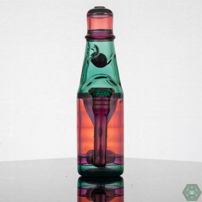 Jack Blew – Mini Ramune Bottle Recycler with 4-Hole Perc. Precision Design: Crafted by Jack Blew Glass, showcasing expert glasswork. Efficient Filtration: Equipped with a 4-hole perc, 10mm female 90° joint, and single drain for smooth recycling. Compact & Stylish: Compact 6" height and 2.5" diameter with a fully faceted joint for added sophistication. Premium Additions: Includes a Headdy Mood Mat, sticker, and business card for added value. Collector's Item: Combines functionality with artistic aesthetics.