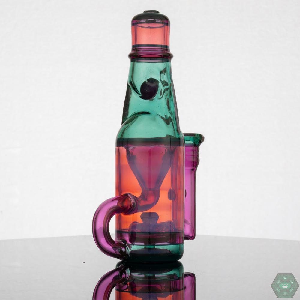 Jack Blew – Mini Ramune Bottle Recycler with 4-Hole Perc. Precision Design: Crafted by Jack Blew Glass, showcasing expert glasswork. Efficient Filtration: Equipped with a 4-hole perc, 10mm female 90° joint, and single drain for smooth recycling. Compact & Stylish: Compact 6" height and 2.5" diameter with a fully faceted joint for added sophistication. Premium Additions: Includes a Headdy Mood Mat, sticker, and business card for added value. Collector's Item: Combines functionality with artistic aesthetics.