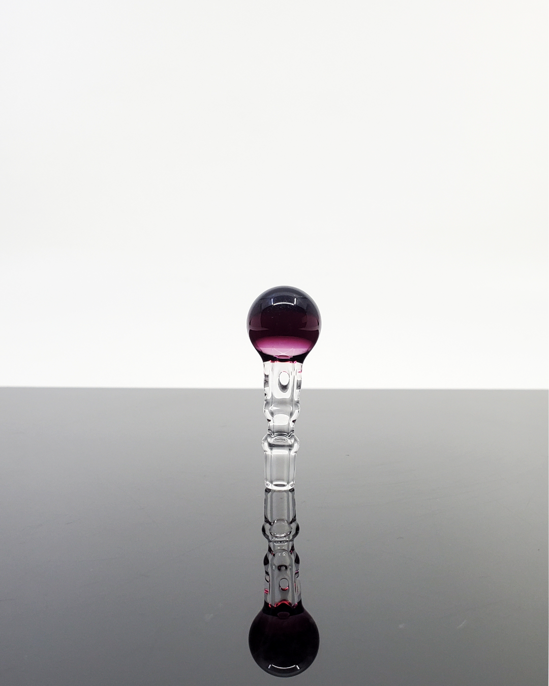 Elegant glass sculpture featuring a striking purple top, set on a sleek, clear stem for a modern artistic display.