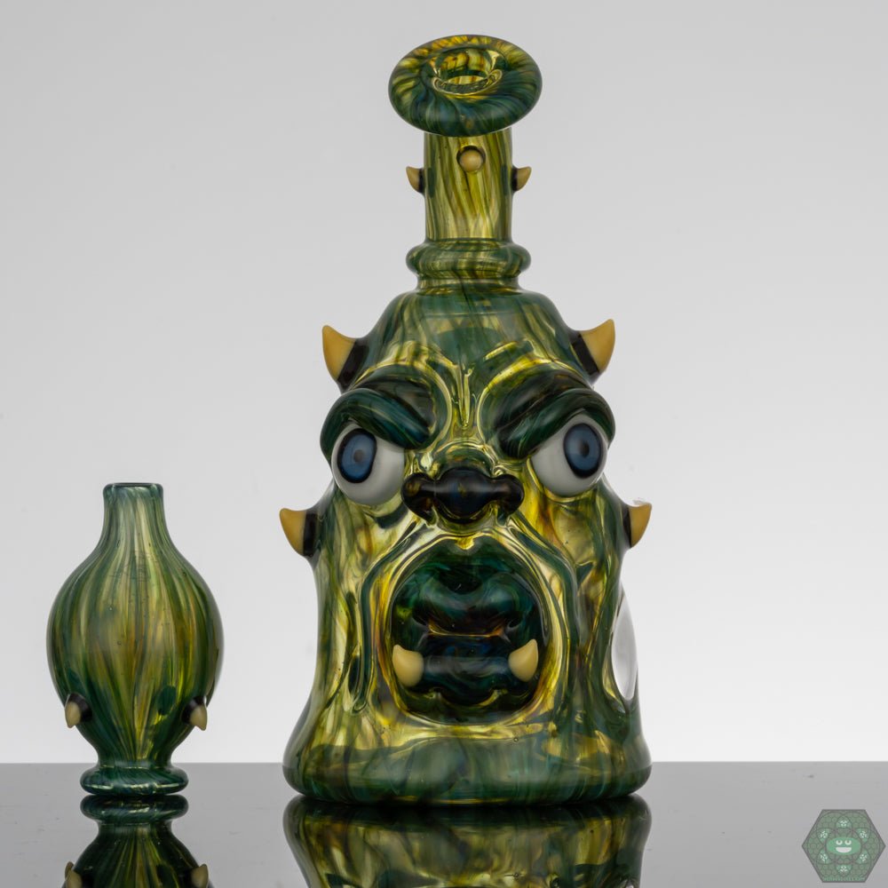  Kaleb Folck GPPR Closed Mouth #330, a UV glass rig with matching bubble cap, crafted by Kaleb Folck as part of the GPPR series, featuring UV-reactive glass for a unique display under light, equipped with a single-hole gil perc and a 10mm female joint, matching bubble cap included, perfect for any glass art collection.


